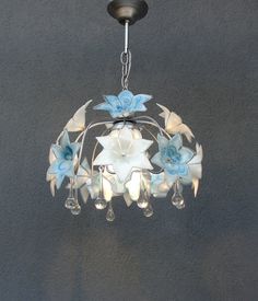 a chandelier hanging from the ceiling with blue flowers on it and clear glass drops