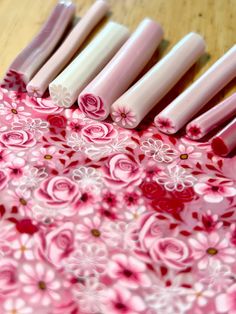 six pink and white candles are lined up in a row on a wooden table top