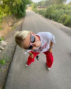 a young boy wearing sunglasses and red pants