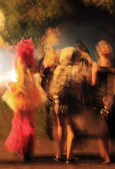 blurry photograph of people walking down the street at night with one person in costume