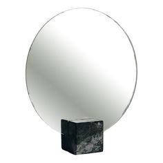 a round mirror sitting on top of a black block