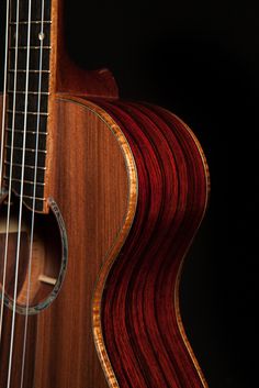 a close up of an acoustic guitar with strings and wood grained body, against a black background