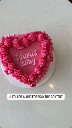 a heart shaped cake with the words taurus baby written on it in pink icing