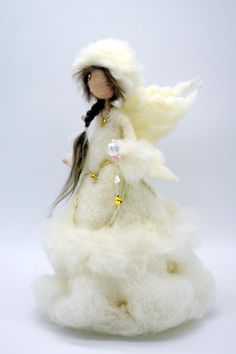 the doll is wearing a white dress with fur on it's head and long hair