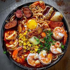 a bowl filled with noodles, shrimp, and other foods on top of a wooden table