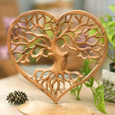 a wooden heart with a tree cut out of it sitting on a table next to a pine cone