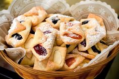 a basket filled with pastries covered in powdered sugar and jelly filling on top of a table