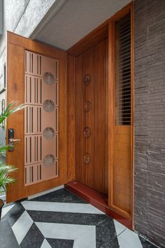 an open wooden door on the side of a building with black and white tile flooring