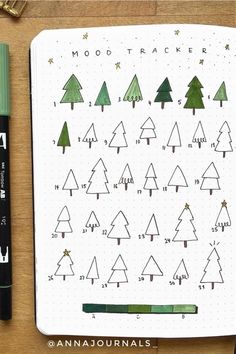 a notebook with christmas trees drawn on it next to a green marker and some writing utensils