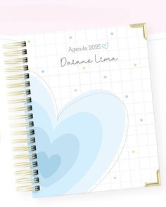 a spiral notebook with a blue heart on the front and back cover, next to a pen