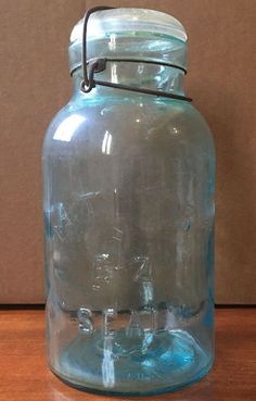 a blue glass jar sitting on top of a wooden table next to a brown wall