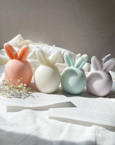 three bunny shaped soaps sitting on top of a white cloth covered tablecloth next to an open book