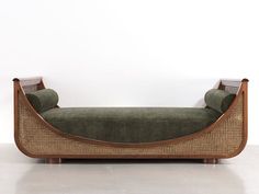 a green couch sitting on top of a white floor next to a wooden frame wall