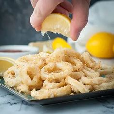 someone is squeezing lemon wedges into some fried food