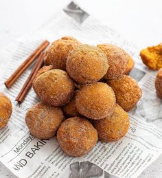 a pile of doughnuts sitting on top of a paper towel next to cinnamon sticks