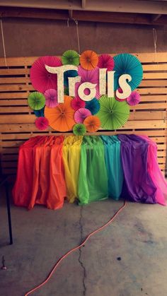 there is a sign that says tails and umbrellas in front of the rainbow colored table cloth