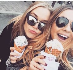 two beautiful young women holding ice cream cones in their hands and posing for the camera