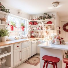 the kitchen is decorated for christmas with red and white decorations on the counters, shelves, and stools