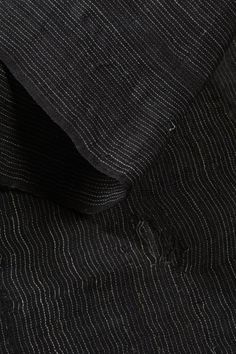 the black and white pinstripe fabric is folded on top of another piece of cloth