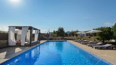 an empty swimming pool with lounge chairs and umbrellas in the sun on a sunny day