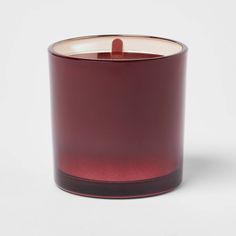 a red glass candle is sitting on a white surface