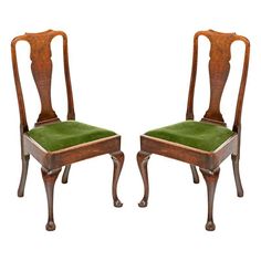 a pair of wooden chairs with green upholstered seats