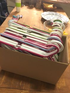 an open box filled with lots of different colored papers on top of a wooden table