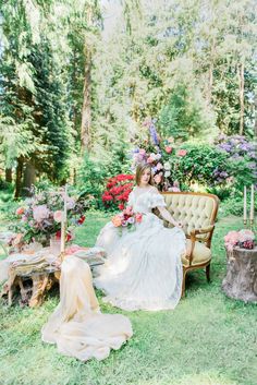 a woman is sitting on a chair in the grass with flowers and candles around her