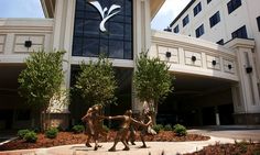 three statues in front of a building with a large sign on it's side