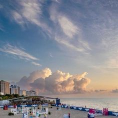 the beach is lined with chairs and umbrellas as the sun sets over the ocean