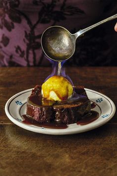 a spoon scooping ice cream over a piece of chocolate cake