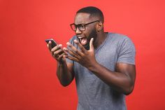 a man holding a cell phone with his mouth wide open and making a funny face