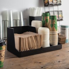 coffee cups and napkins are sitting on a wooden table in front of the disposable cup holders