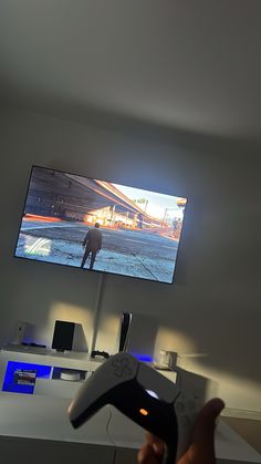 a person holding a video game controller in front of a flat screen tv on a wall