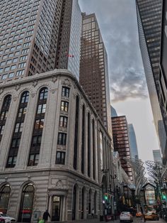 a city street filled with tall buildings next to traffic and people walking on the sidewalk