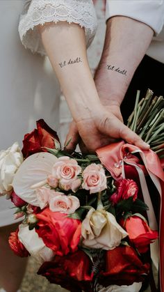 two people holding hands with tattoos on their arms and flowers in the other hand,