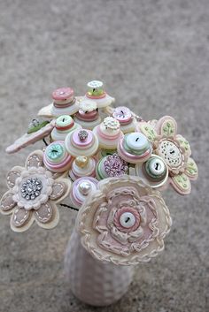 a vase filled with buttons and flowers on top of a cement ground next to a sidewalk