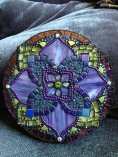 a purple and green mosaic design on a piece of glass sitting on top of a couch