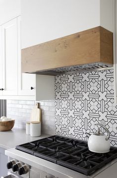 a stove top oven sitting inside of a kitchen next to white cabinets and counter tops