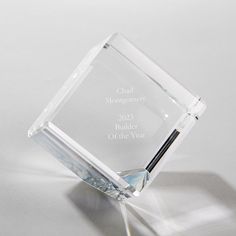 a clear glass award with a black pen sticking out of it's center piece