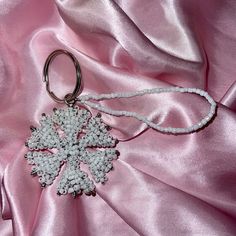 a snowflake ornament hanging from a pink satin material with beading