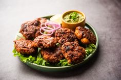 a green plate topped with meat and lettuce next to a bowl of sauce