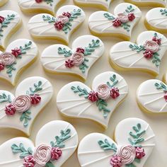 heart shaped cookies decorated with flowers and leaves on a white tablecloth covered in icing