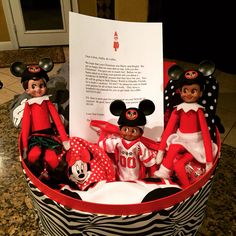 two elfs are sitting in a basket with mickey and minnie mouse dolls on it