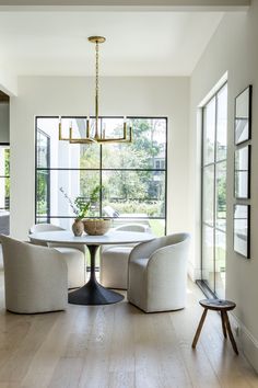 a dining room table with chairs and a chandelier in front of large windows