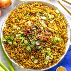 a bowl filled with rice and vegetables next to some chopsticks on the side