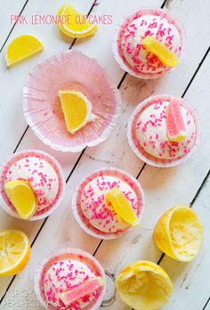 cupcakes decorated with sprinkles and lemon slices on pink paper plates