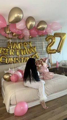 a woman sitting on top of a bed in front of balloons that say happy 21st birthday