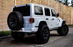 a white jeep parked next to a brick wall