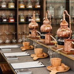 several copper kettles and cups on display in a store